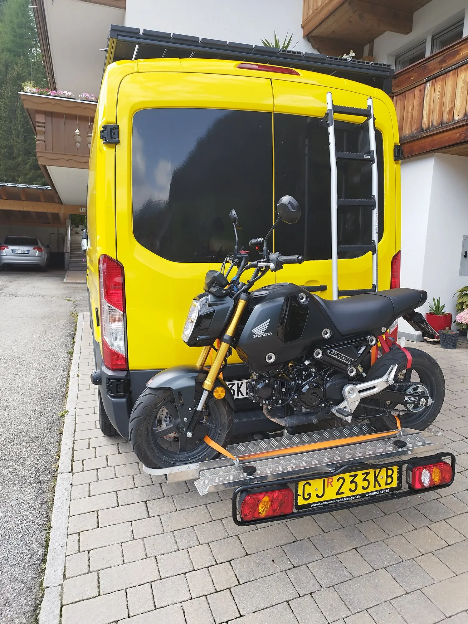 Kleines Motorrad auf dem Träger an der Anhängerkupplung des gelben Vans