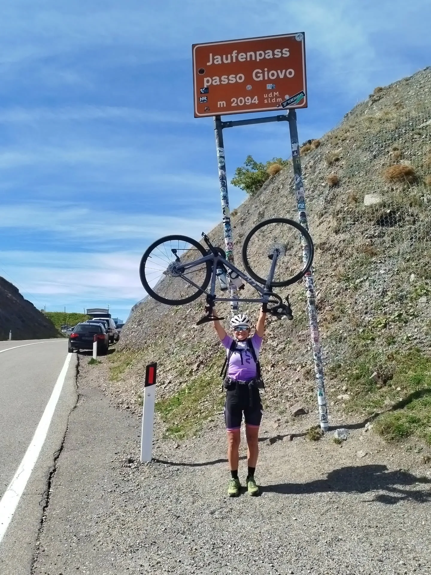 Edith stemmt das Rennrad am Jaufenpass-Schild in die Höhe
