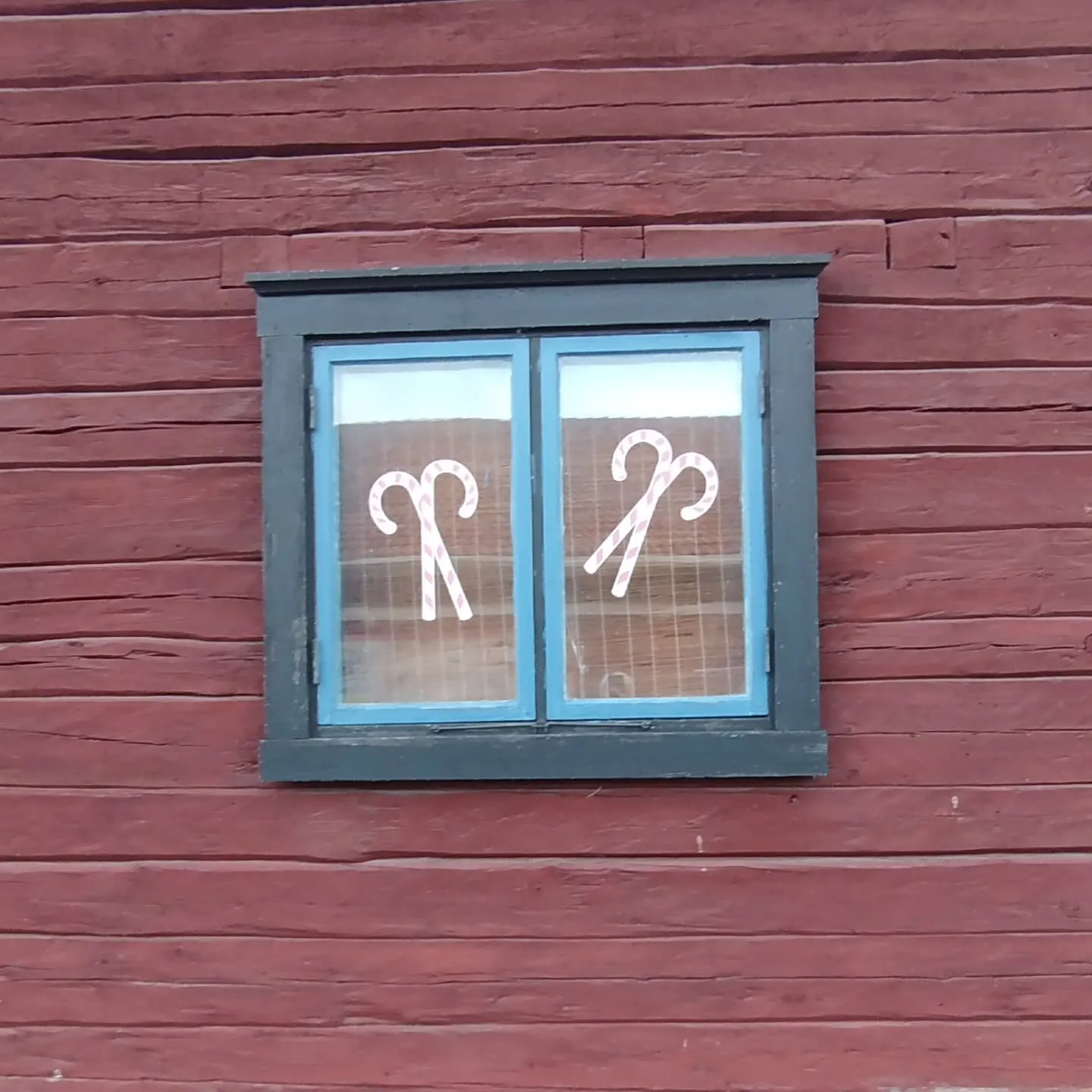 Rotes Holzhaus mit Zuckerstangen im Fenster