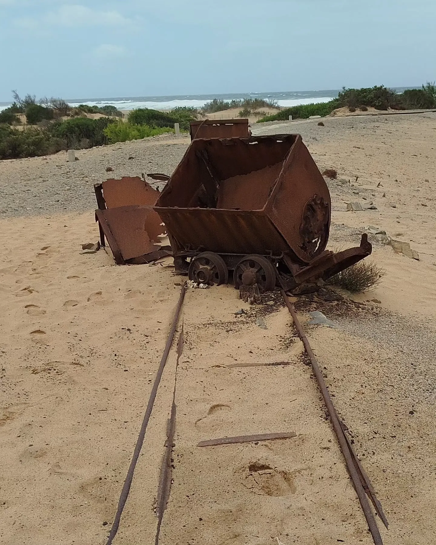 Rostiger Grubenwagen auf alten Schienen in den Dünen