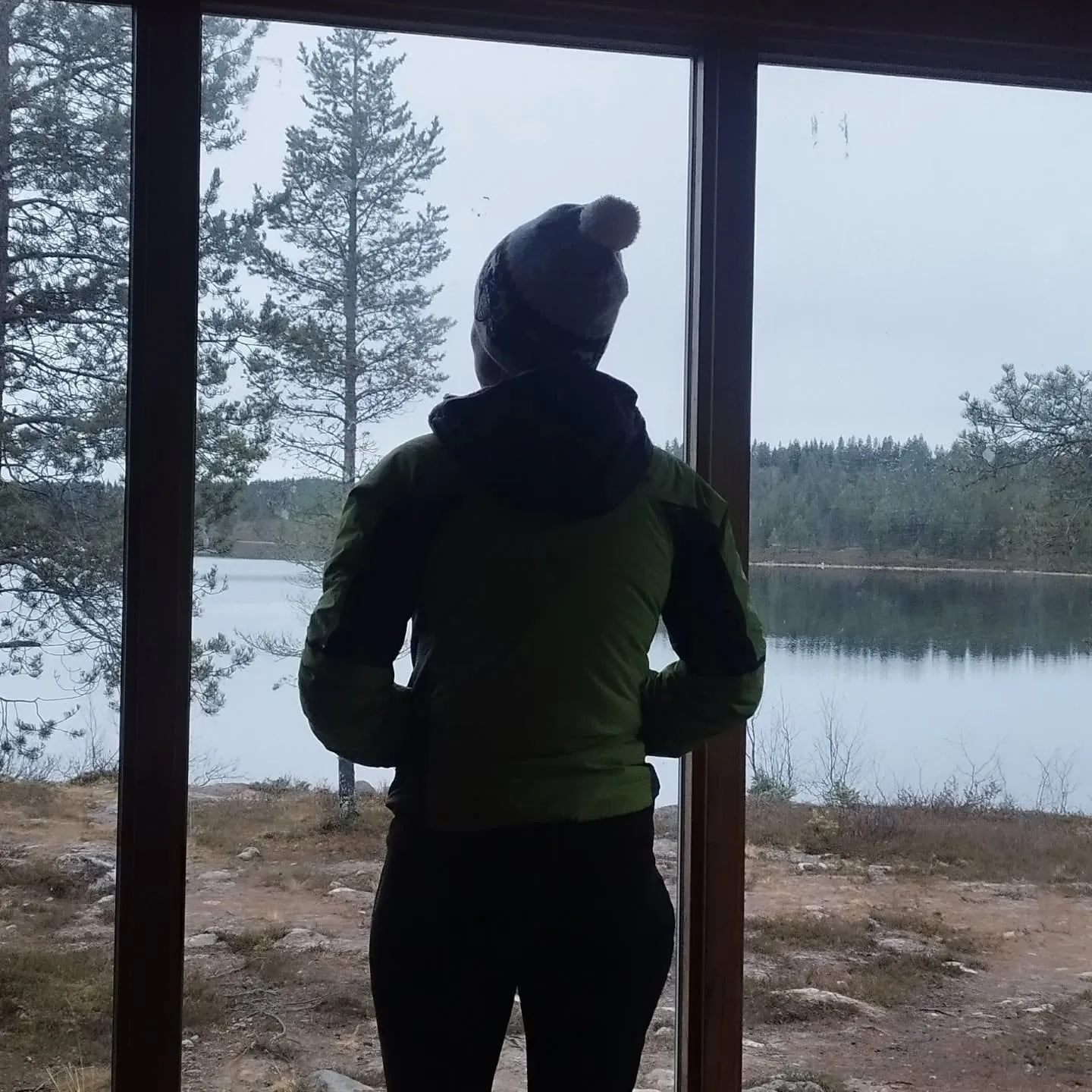 Edith am Fenster der Wildnishütte mit Blick auf den See