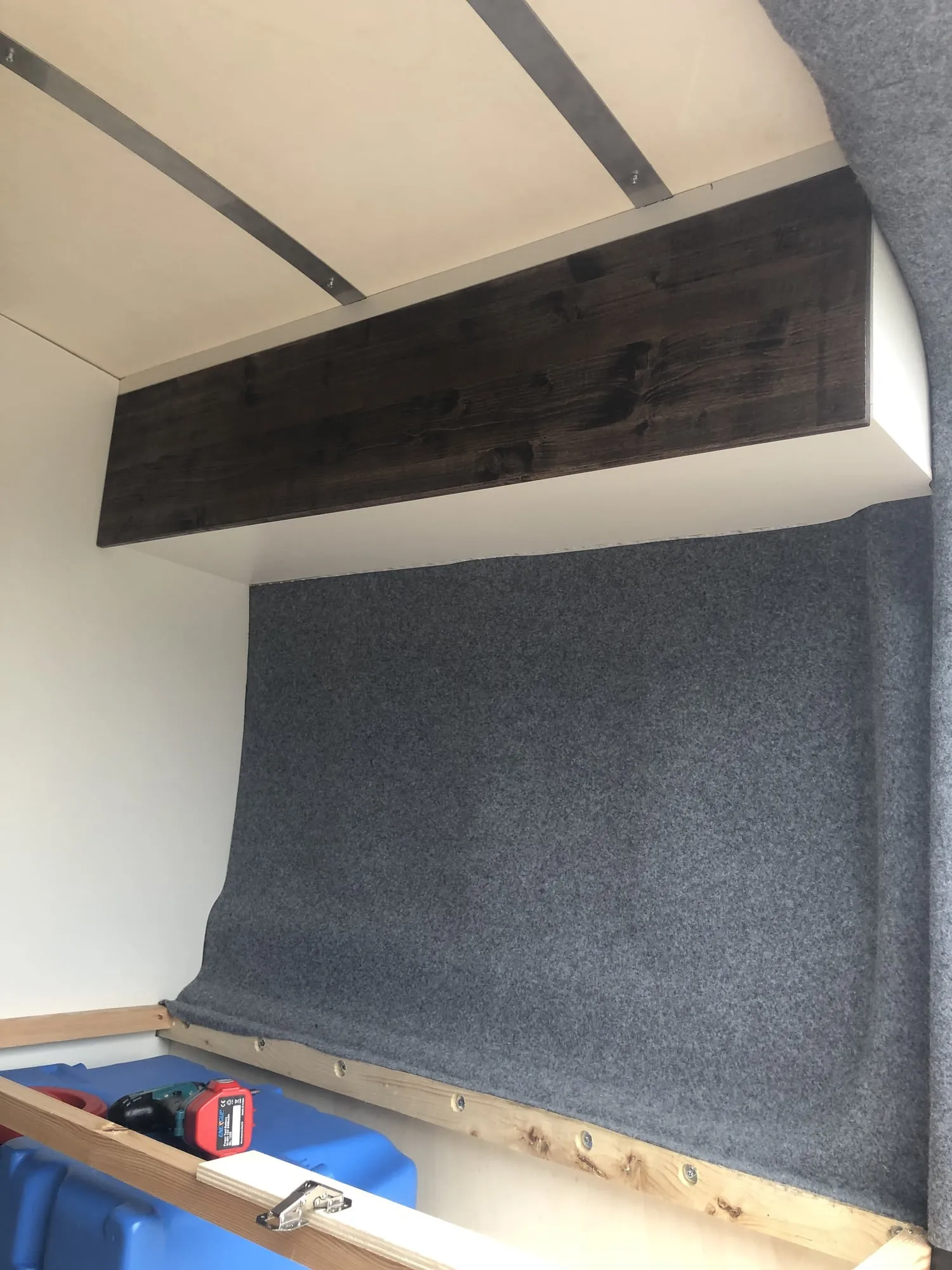 Hängeschrank aus dunklem Holz über der Filzwand